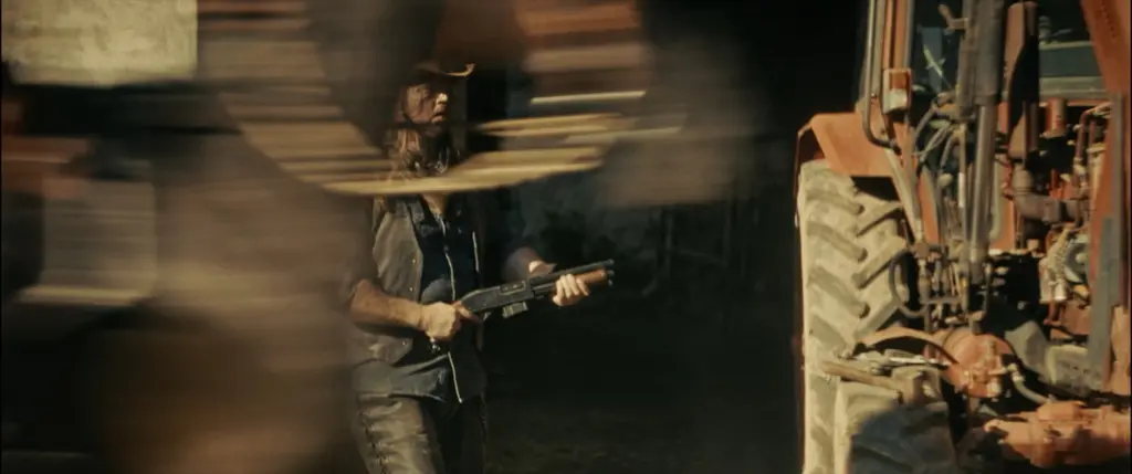 Long-haired man in a denim vest gripping a pump-action shotgun beside an orange tractor, motion blur - Amon Amarth