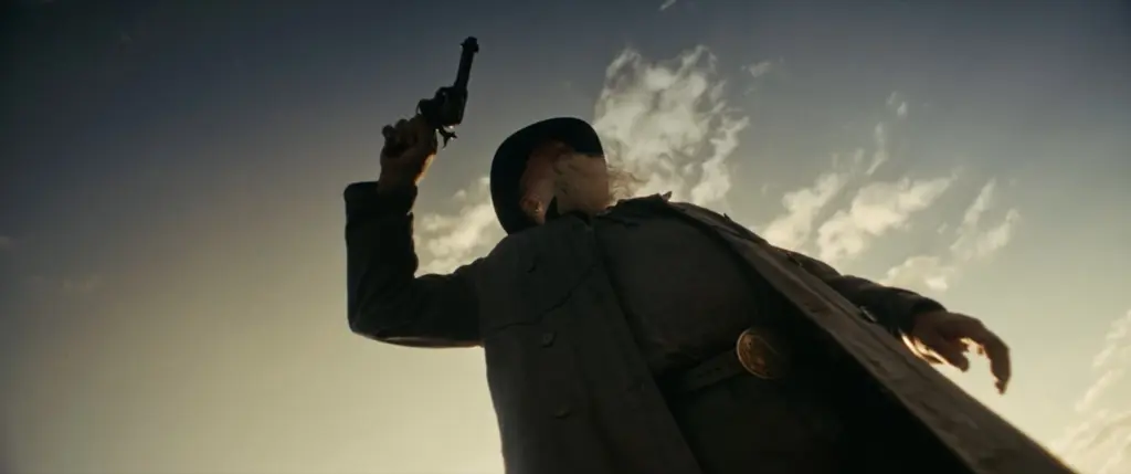 Low-angle silhouette of a long-bearded man in a duster raising a revolver to the sky - Amon Amarth