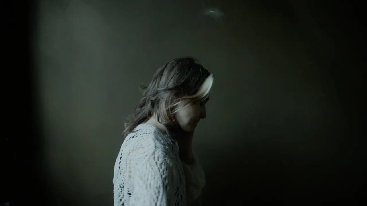 Woman in profile turning away from the window, soft window light on her hair