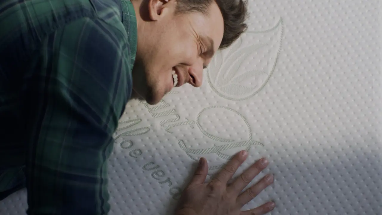 Man's face resting contentedly against a pillow with a leaf-shaped brand tag - Plantpur commercial