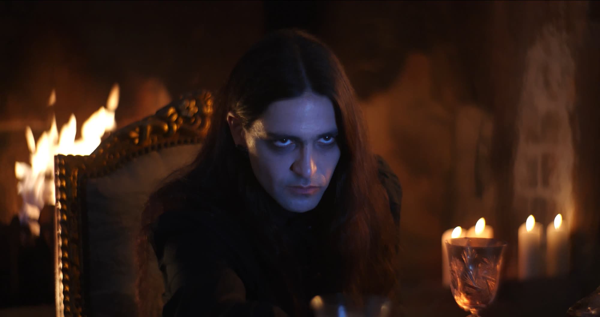 Ater music video still - close-up by firelight, candles and a crystal glass in the foreground