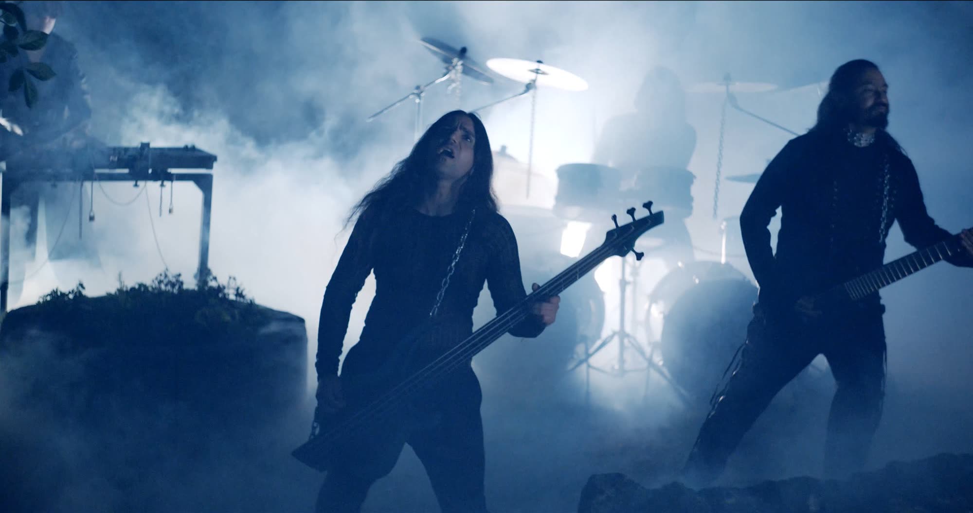 Ater music video still - band performing in fog on a stone stage lit blue