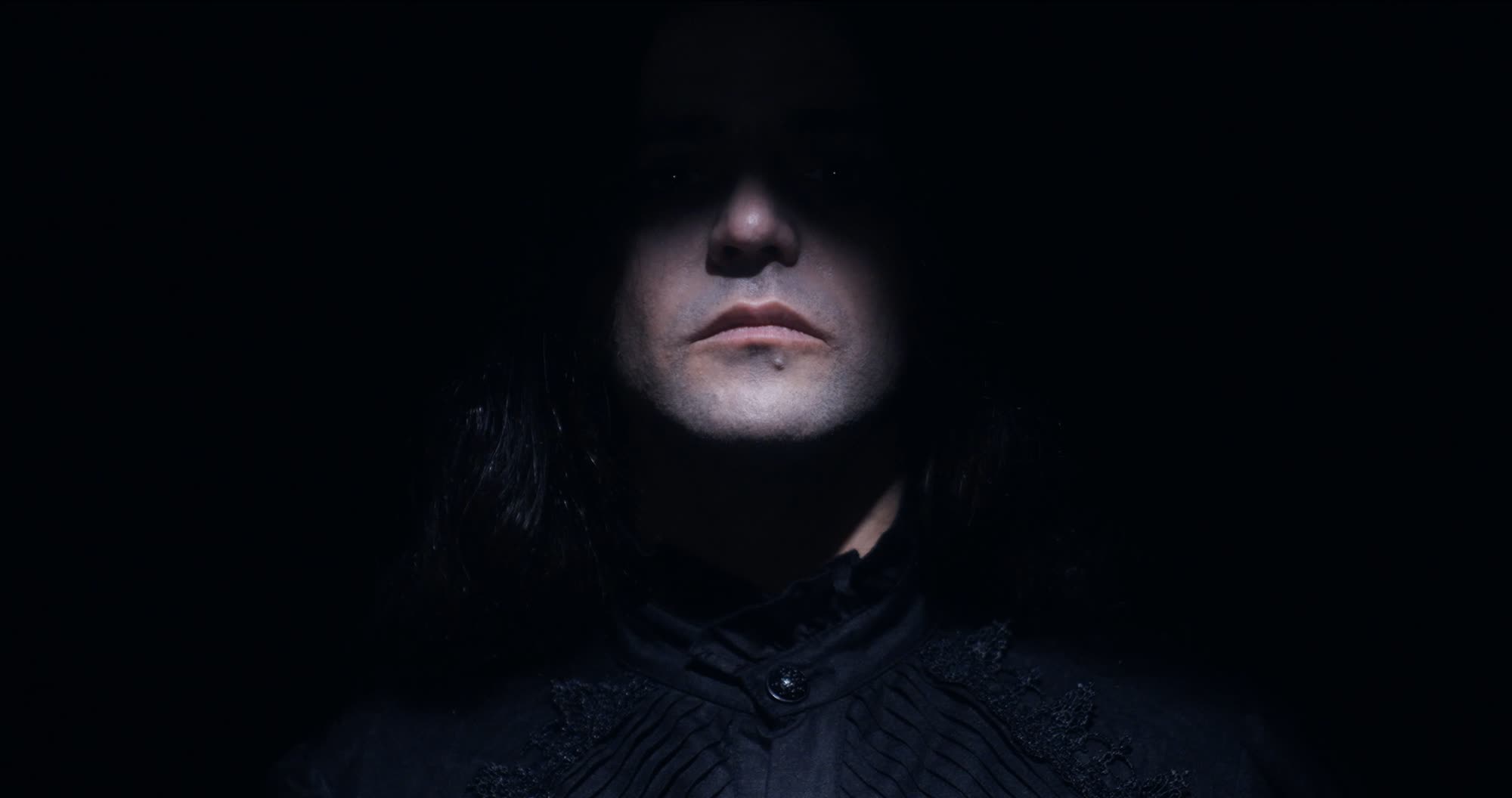 Ater music video still - close-up portrait in near darkness, face barely lit