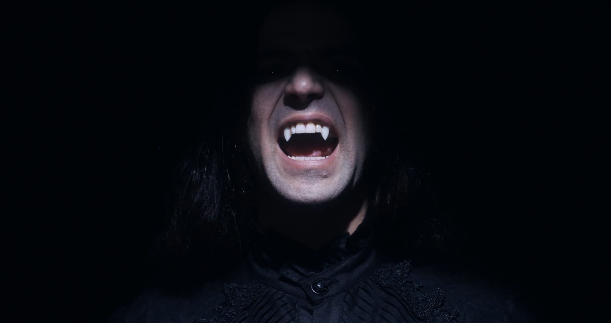 Ater music video still - close-up of a figure baring vampire fangs, screaming into camera