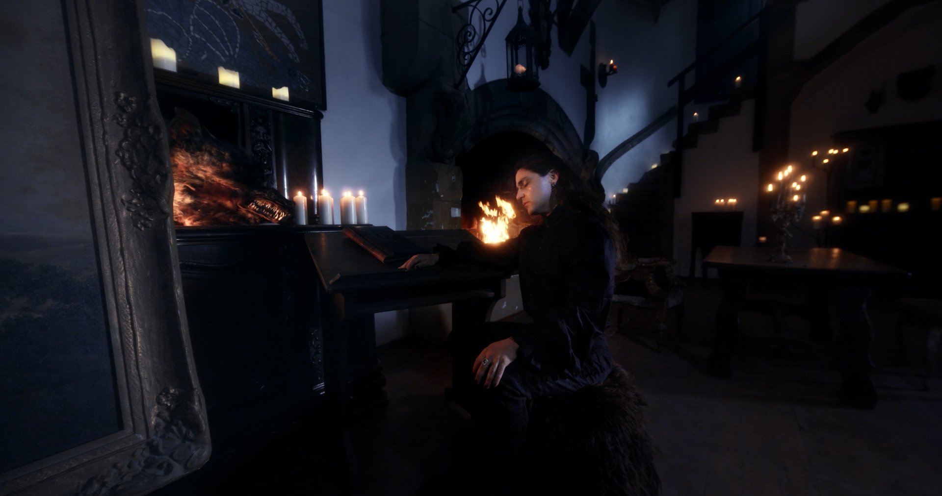 Ater music video still - figure seated beside a lit fireplace, reading by candlelight