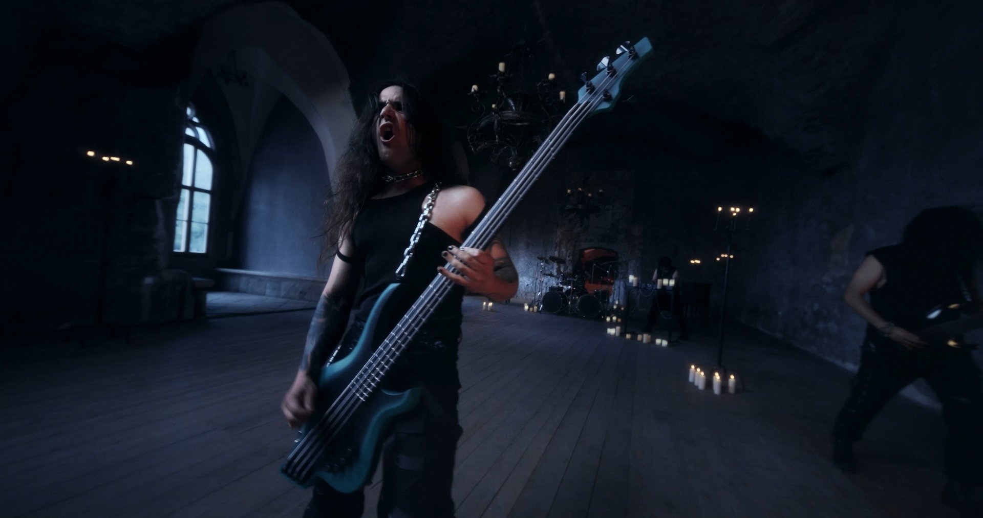 Ater music video still - bassist singing, full band visible across the candlelit hall
