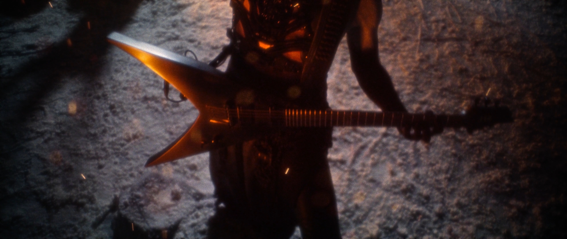 Behemoth Mystic still - close-up of a spiked guitar body lit warm orange against a snowy backdrop