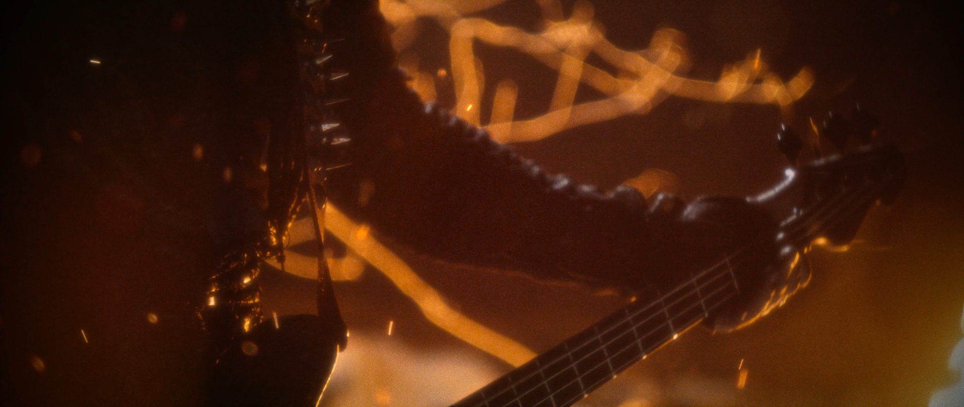 Behemoth Mystic still - abstract close-up of a spiked shoulder pauldron and guitar neck against streaking firelight