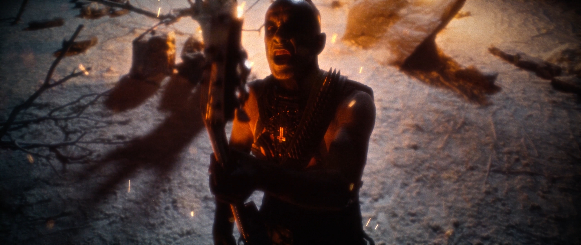 Behemoth Mystic still - corpsepainted frontman screaming over a guitar amid burning branches and embers