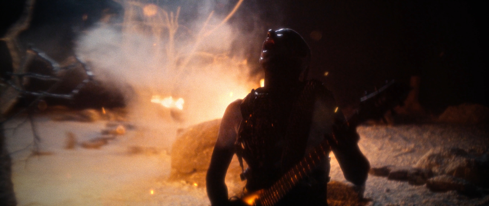 Behemoth Mystic still - silhouetted figure in a spiked harness, head thrown back before a bonfire