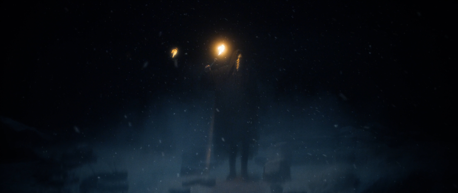 Behemoth Mystic still - distant hooded figure holding a lit torch aloft in a snowstorm