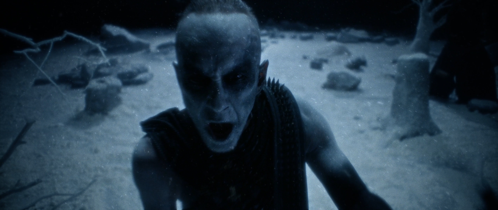 Behemoth Mystic still - corpsepainted figure with spiked shoulder armor screaming among snow-covered standing stones