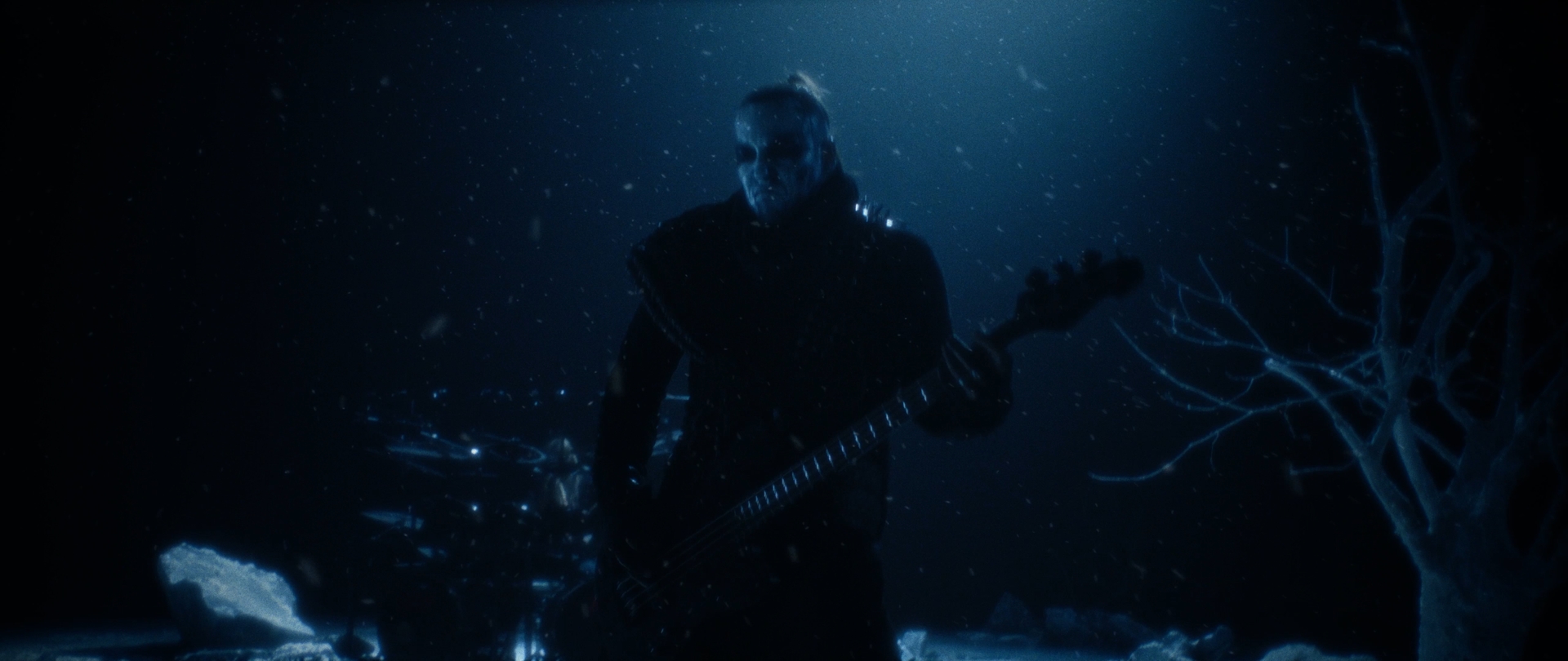 Behemoth Mystic still - corpsepainted bassist performing before a drum kit in a snowstorm
