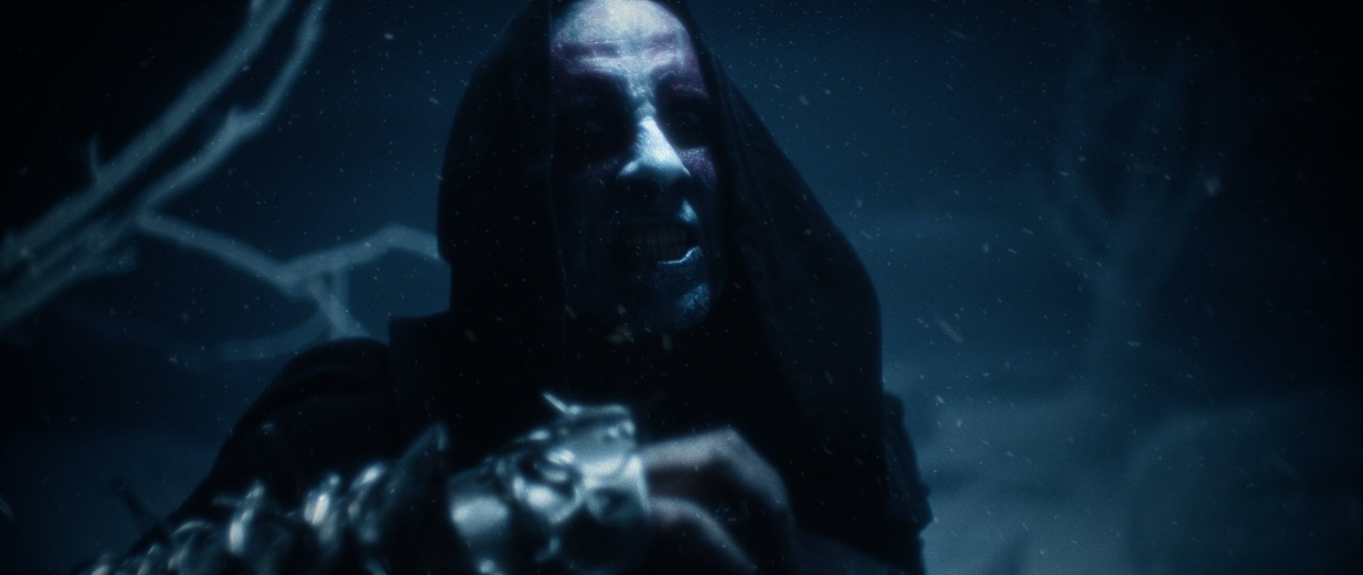 Behemoth Mystic still - close-up of a hooded, corpsepainted figure raising a spiked gauntlet