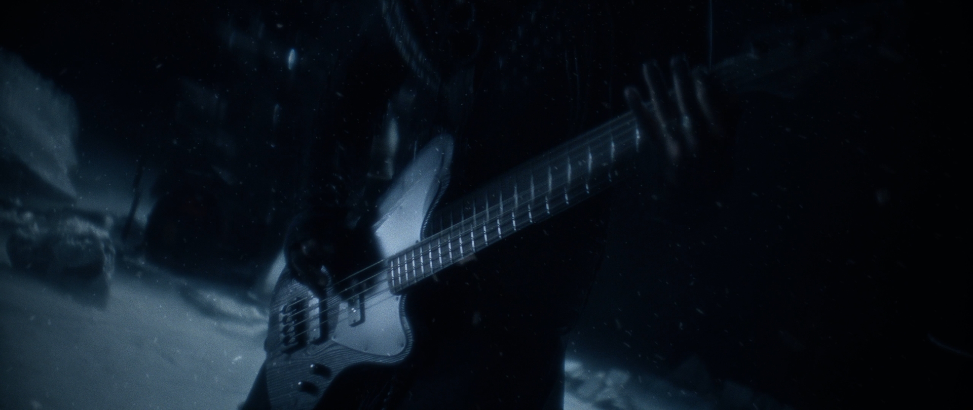 Behemoth Mystic still - close-up of a hand fretting a bass guitar in falling snow