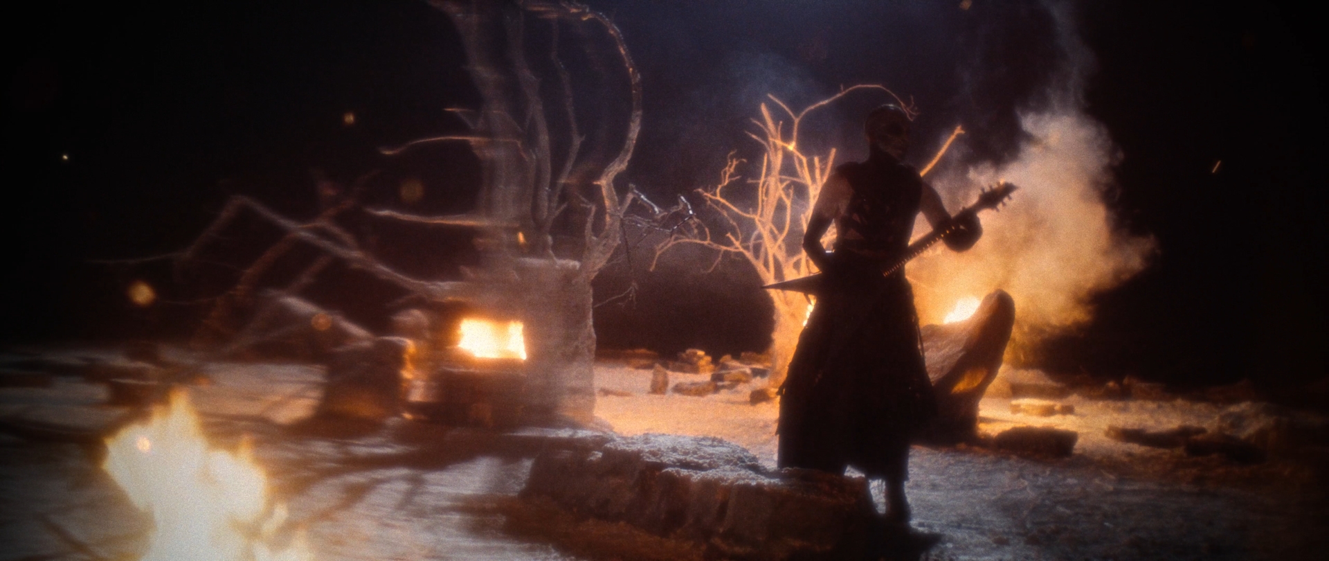 Behemoth Mystic still - guitarist silhouetted between bonfires among gnarled, snow-dusted trees