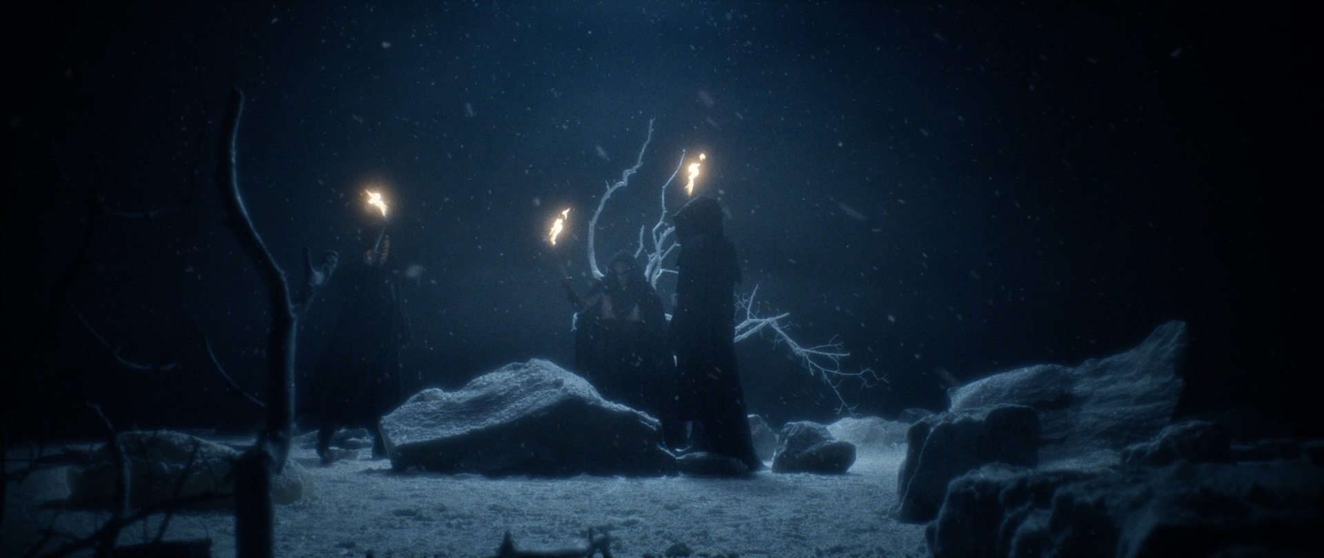 Behemoth Mystic still - three hooded figures carrying torches through a snow-covered, rocky field