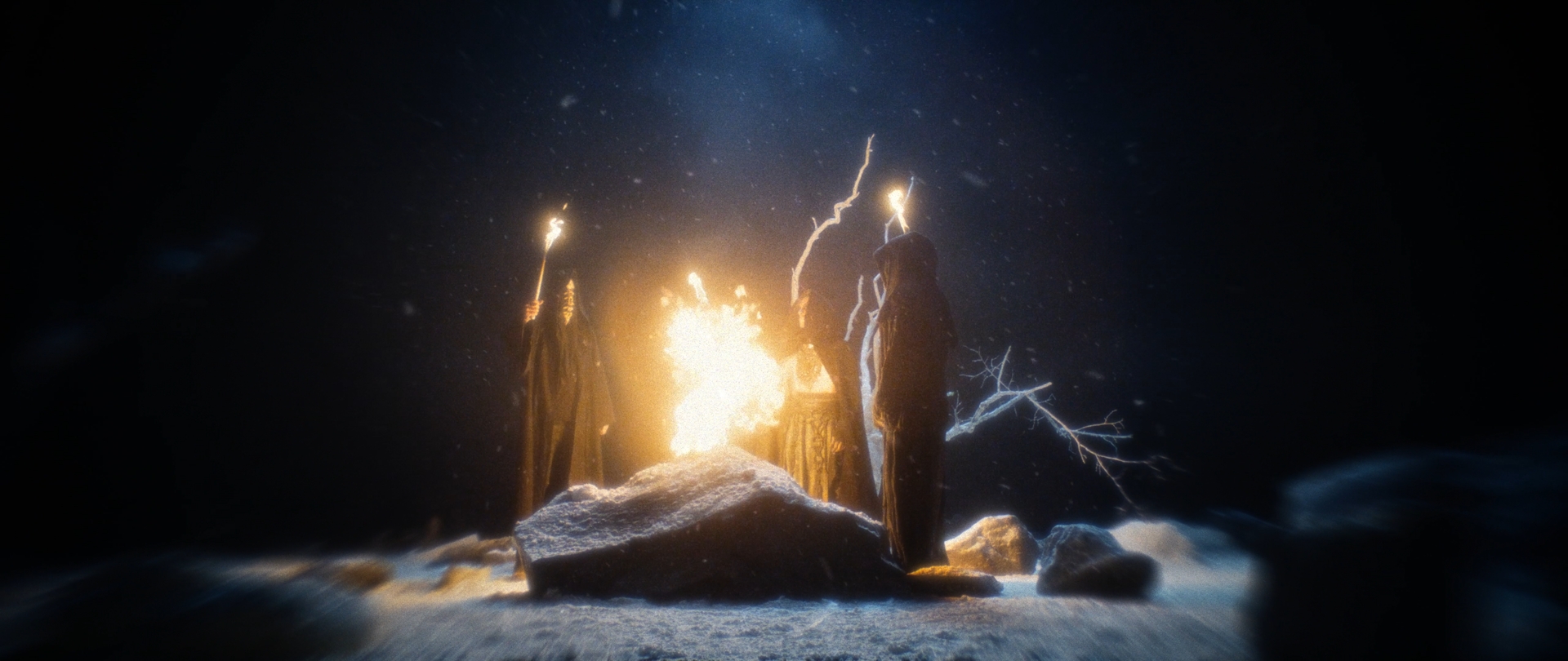 Behemoth Mystic still - hooded figures gathered around a bonfire with torches raised in falling snow