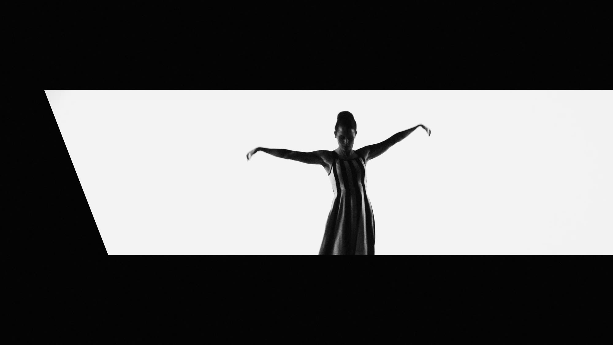 Dzień i noc still - graphic wide shot, figure in a striped dress with arms outstretched against a white backdrop