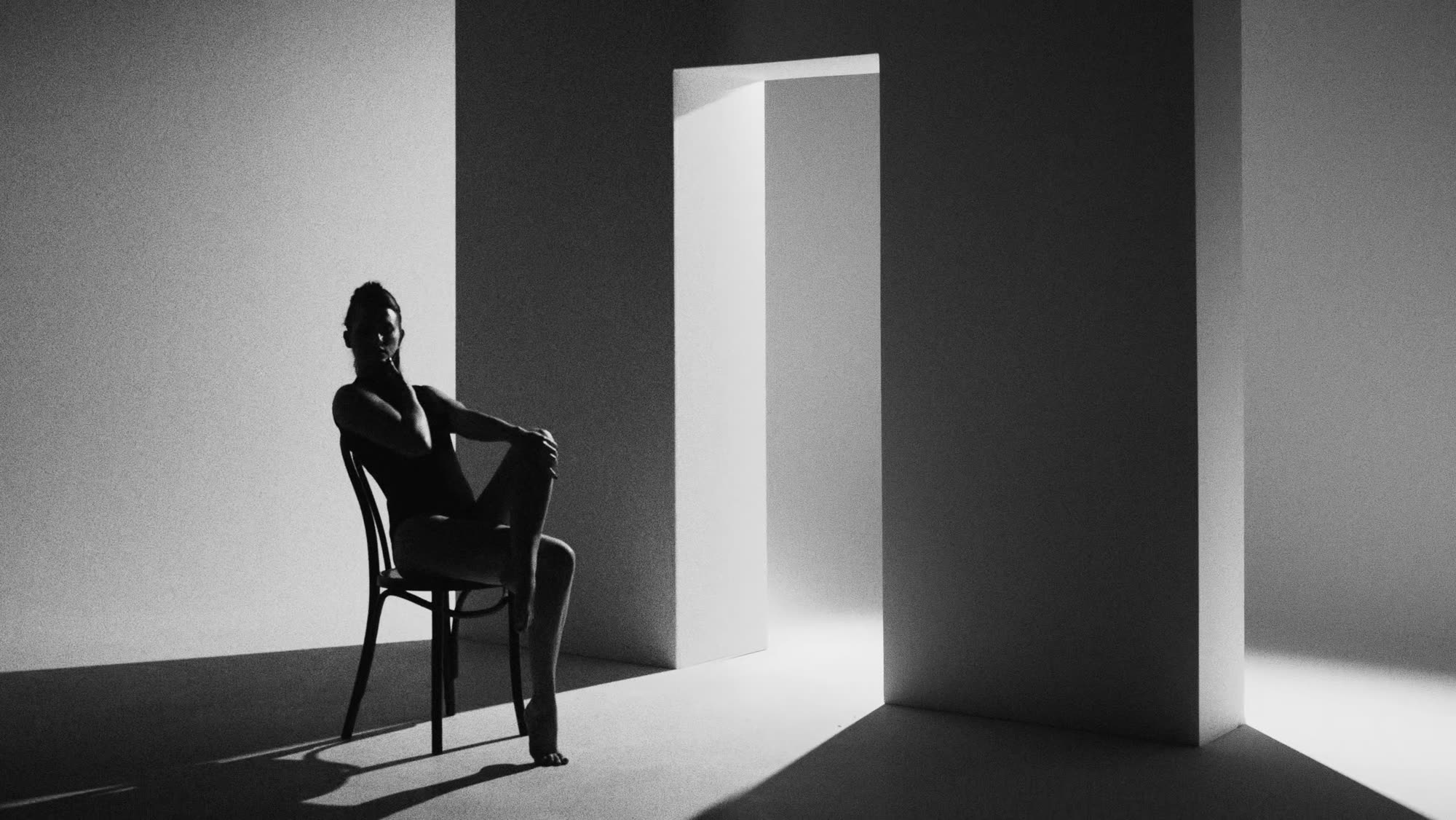 Dzień i noc still - silhouette seated on a chair in a stark white doorway