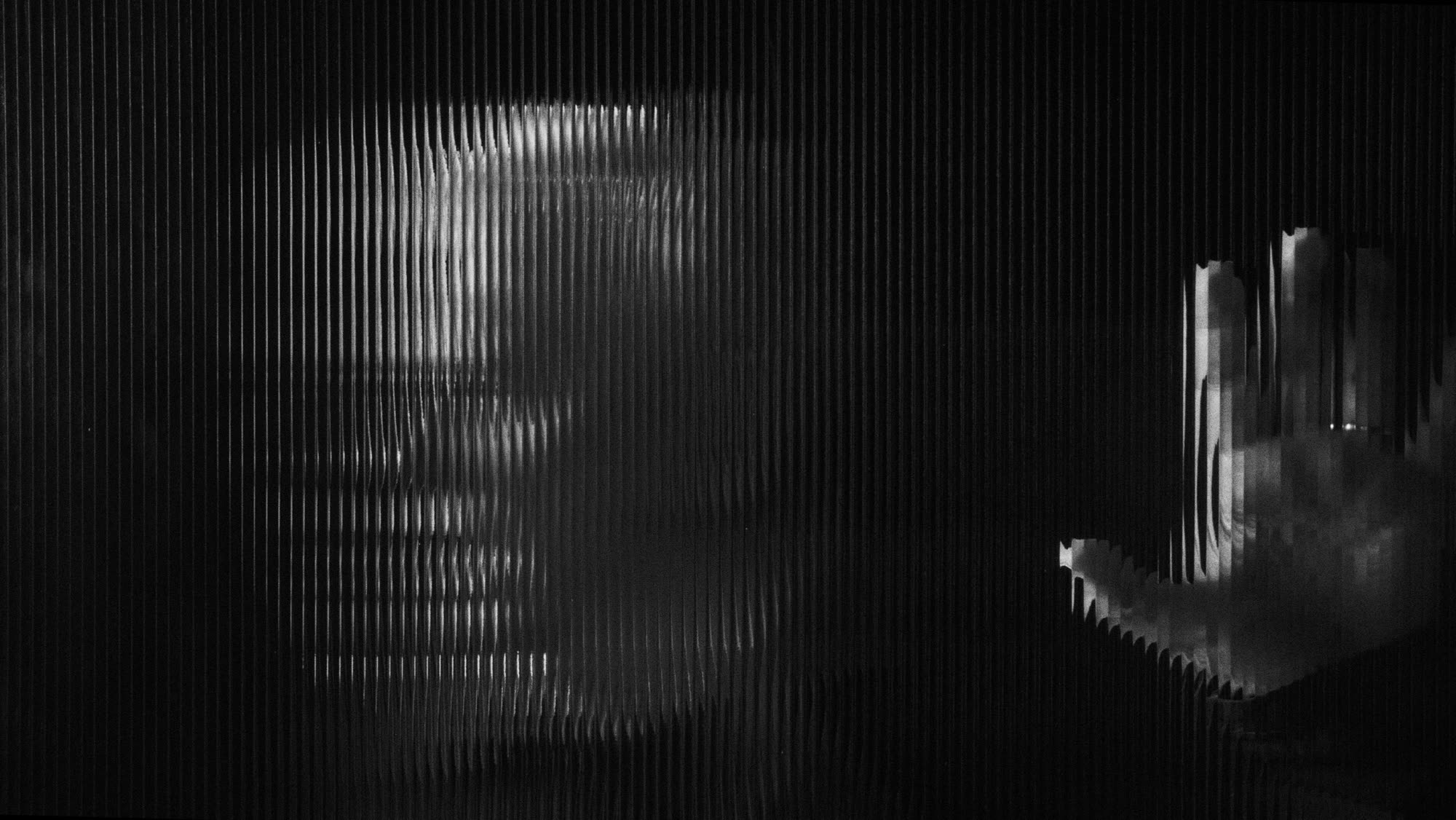 Dzień i noc still - abstract face and hand behind reeded glass, high contrast black and white