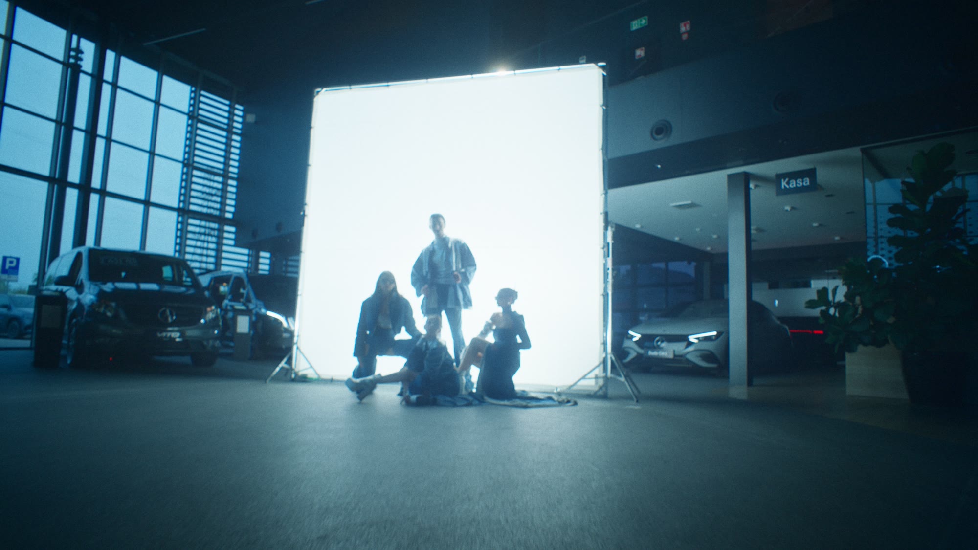 Group of models silhouetted against a large light panel inside a car showroom - Wrocław Fashion Week