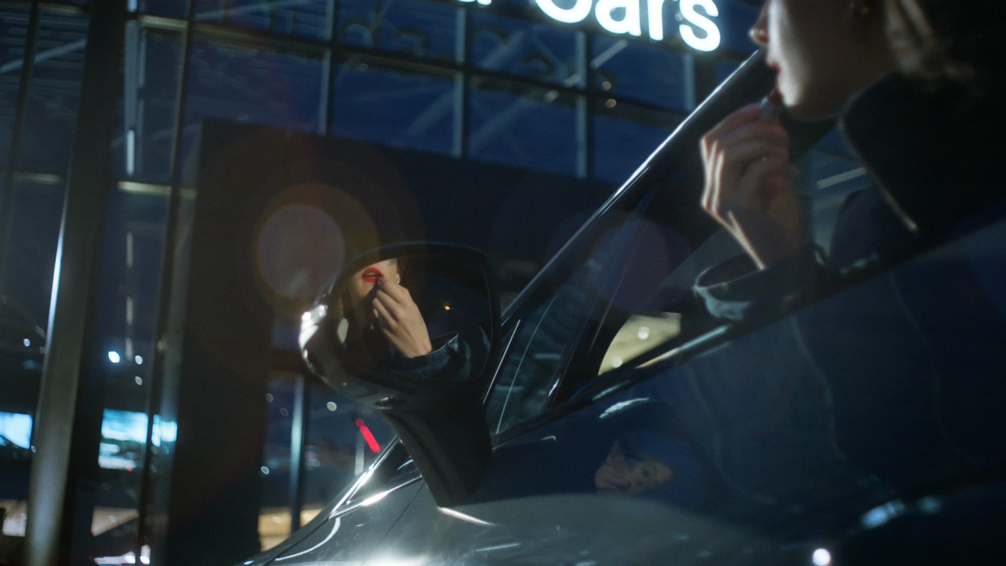 Close-up reflection in a car side mirror, model applying red lipstick - Wrocław Fashion Week