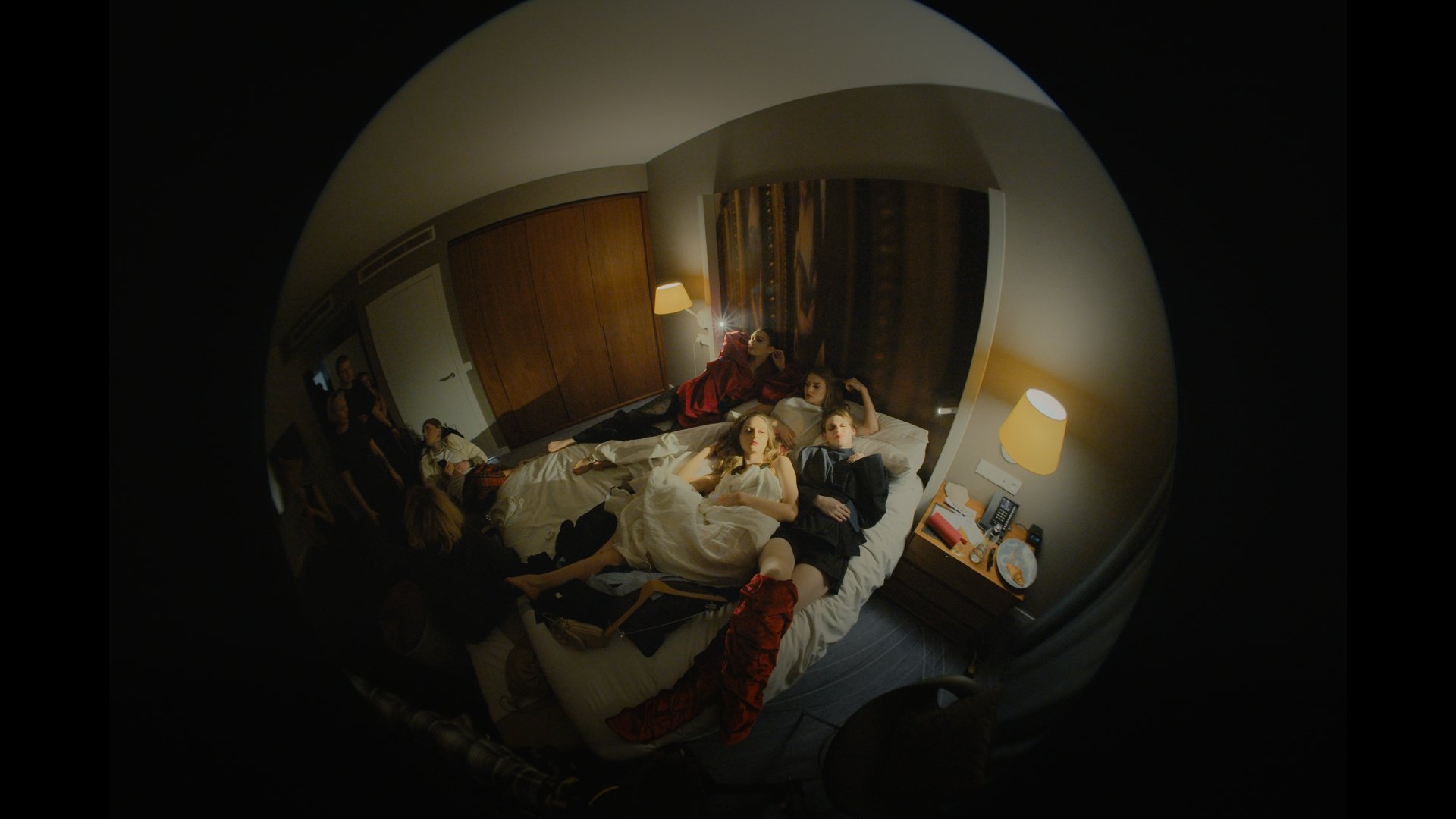 Fisheye shot of a hotel bedroom with clothes and props laid out