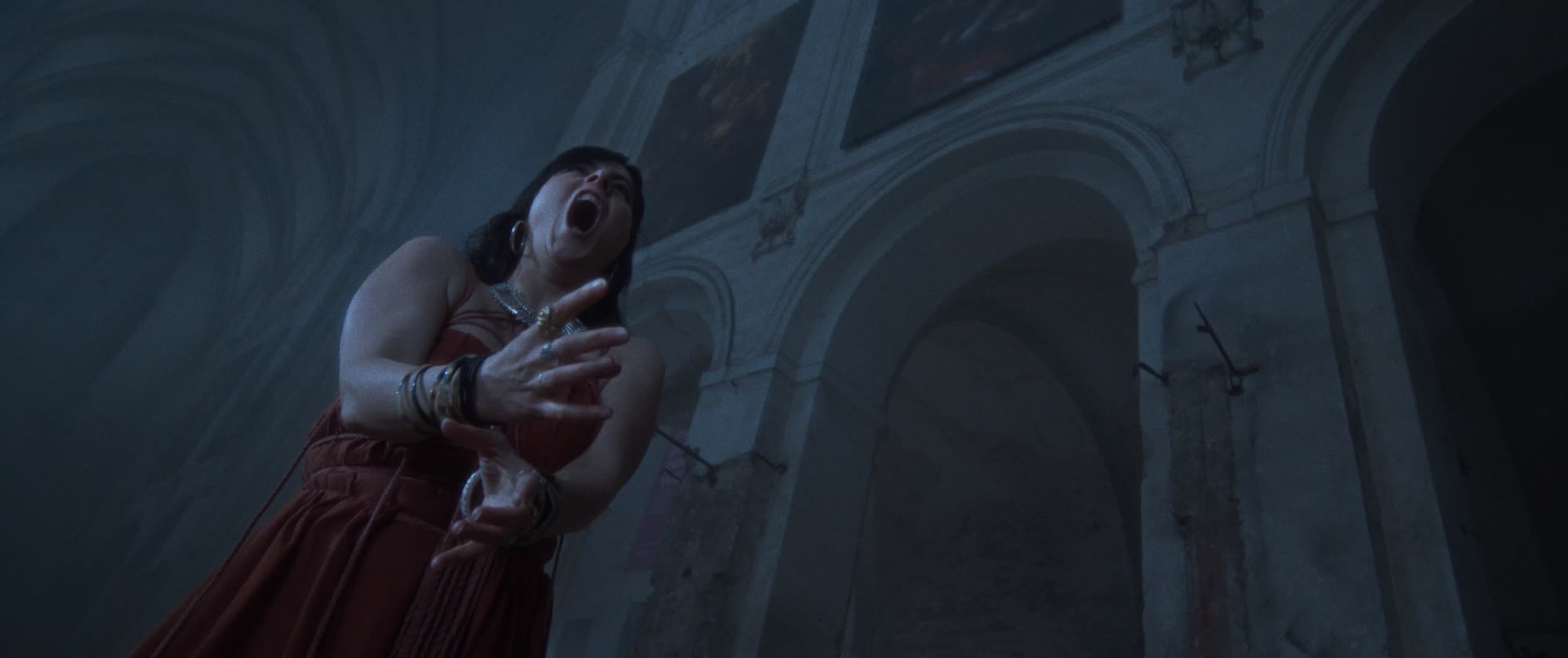 IGORRR music video still - woman screaming, lit from below inside a cathedral colonnade
