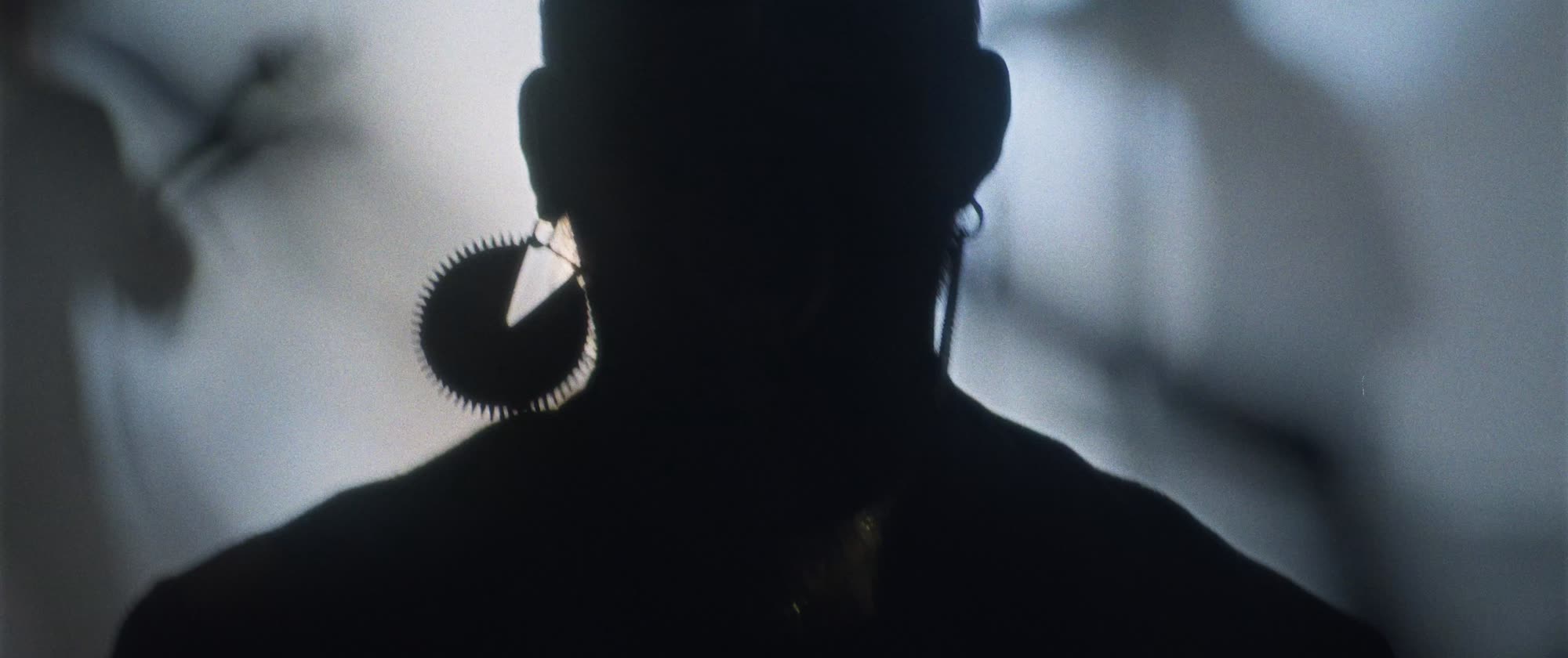 IGORRR music video still - silhouette portrait with a spiked hoop earring, backlit