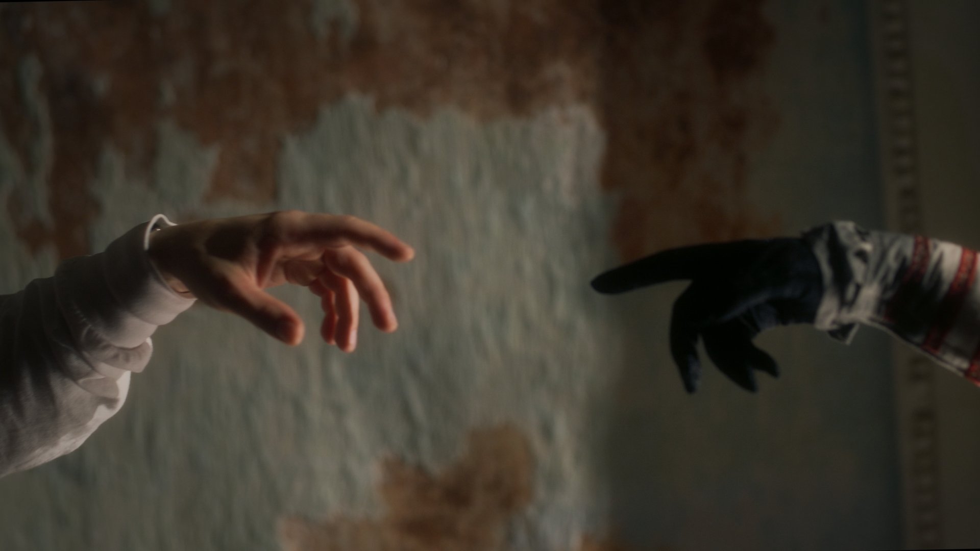 Jestem Alpha still - two reaching hands almost touching, one human and one clawed, echoing the Creation of Adam
