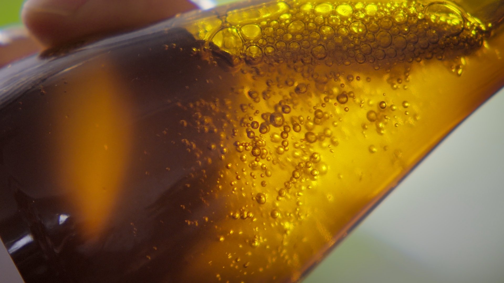 Close-up of amber liquid pouring, catching the light - Miastolas commercial