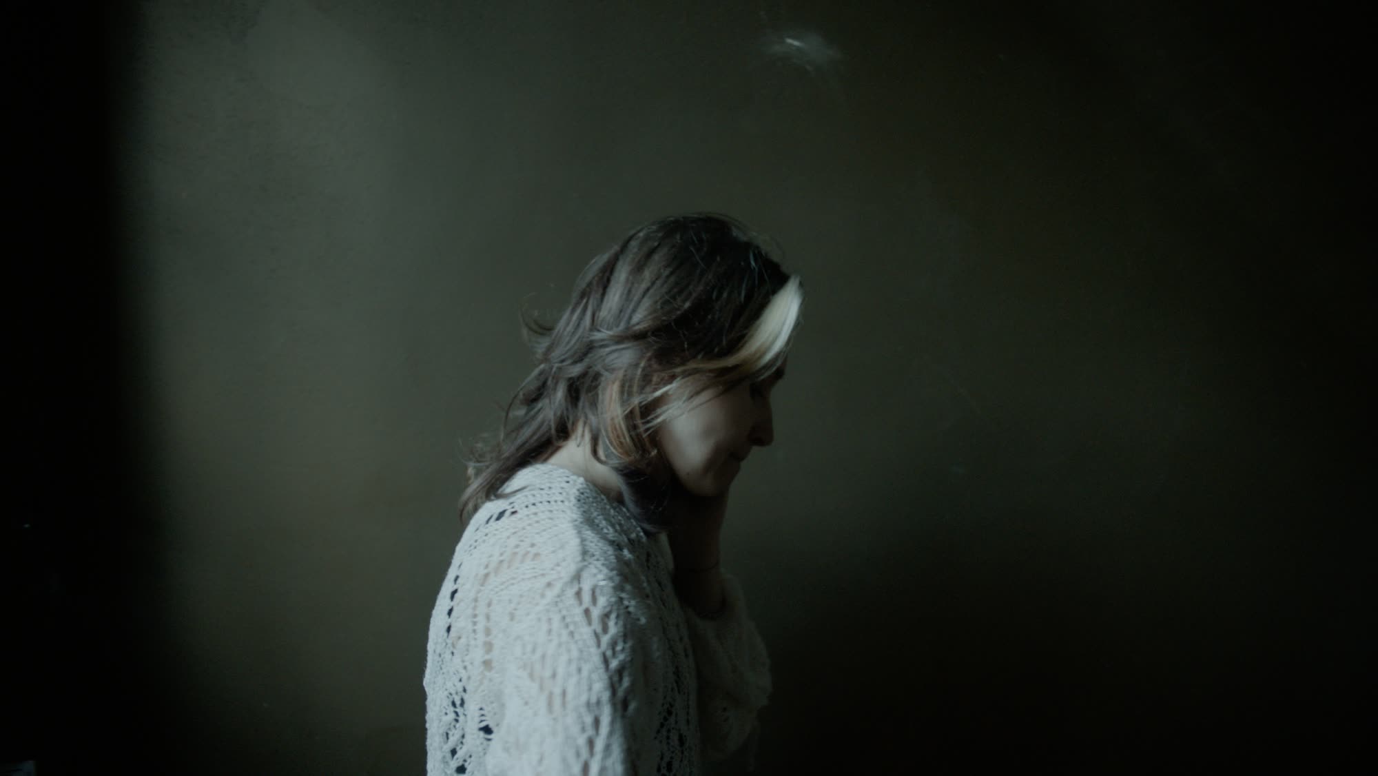 Woman in profile turning away from the window, soft window light on her hair