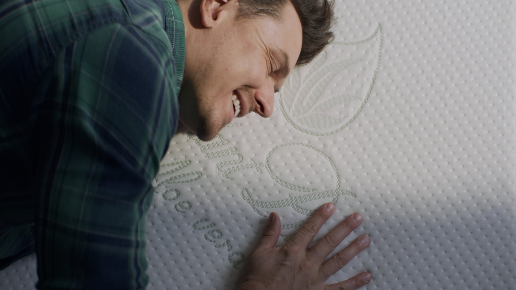 Man's face resting contentedly against a pillow with a leaf-shaped brand tag - Plantpur commercial
