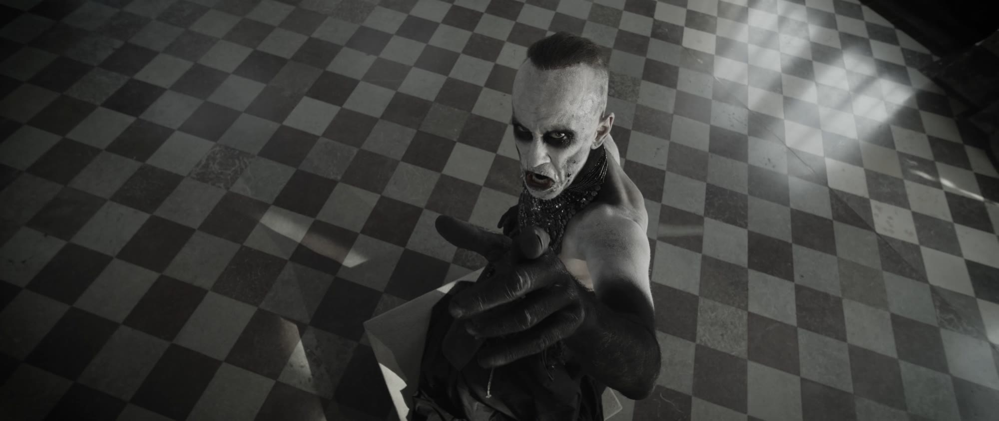 Behemoth music video still - figure pointing directly at the camera from above, on the checkered floor