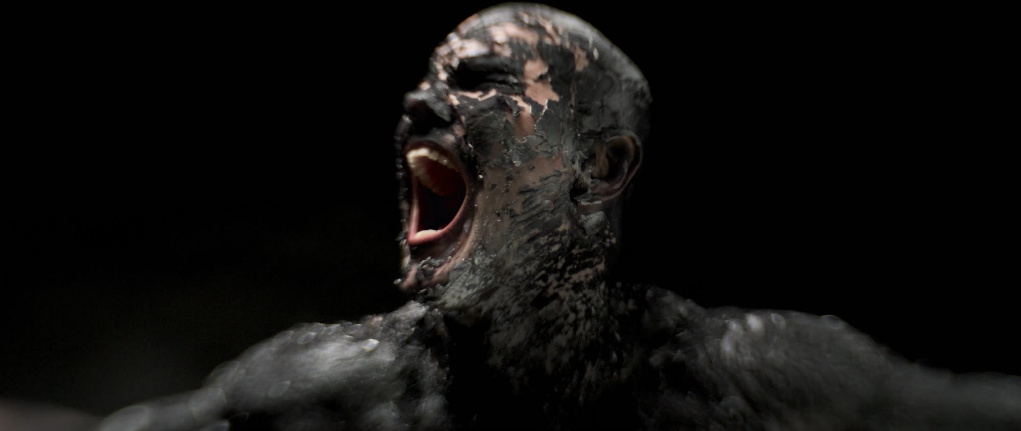 Behemoth music video still - screaming tar-covered face in close-up