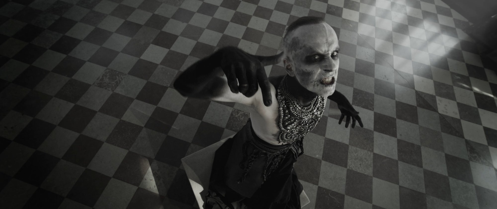 Behemoth music video still - hooded figure standing centered in a grand doorway of a baroque hall