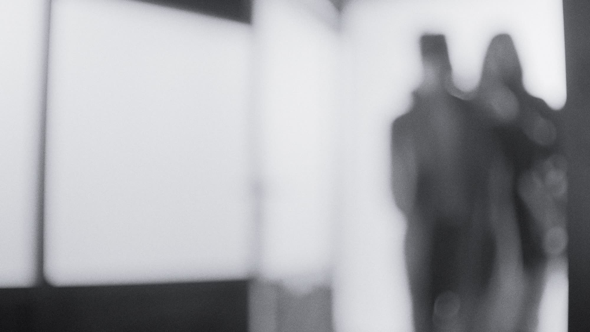 Blurred silhouettes of two figures in a bright doorway