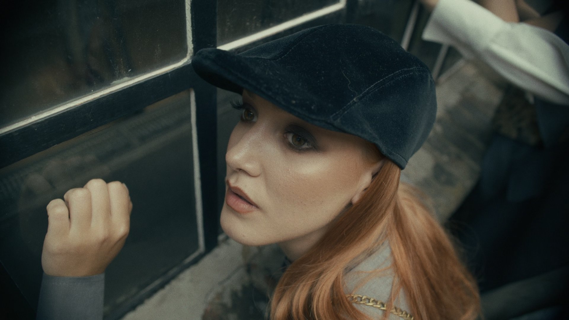 Woman in a cap reflected in a car window, hand raised - Wrocław Fashion Week Collections