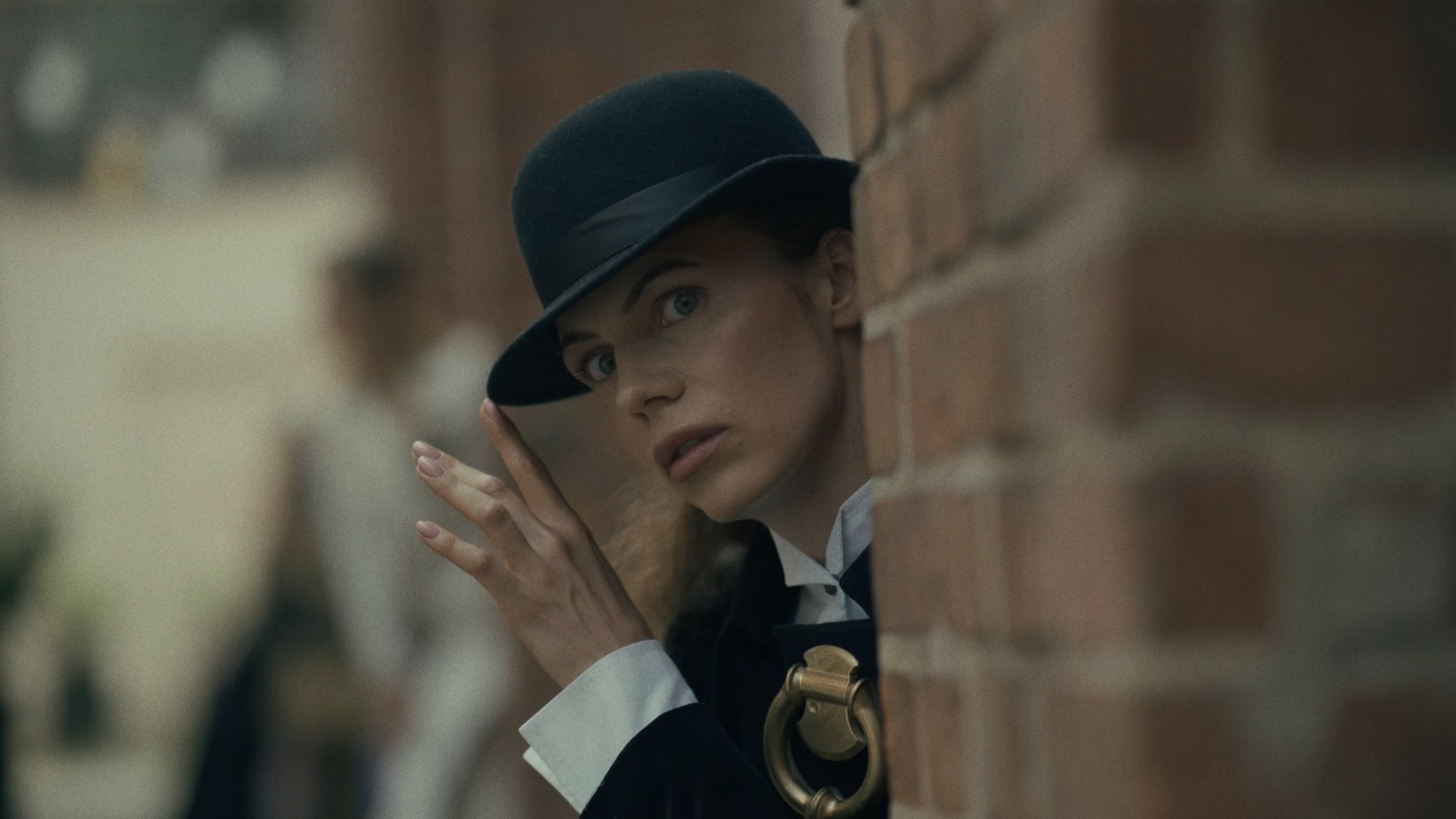 Portrait of a woman in a dark hat leaning against a brick wall - Wrocław Fashion Week Collections