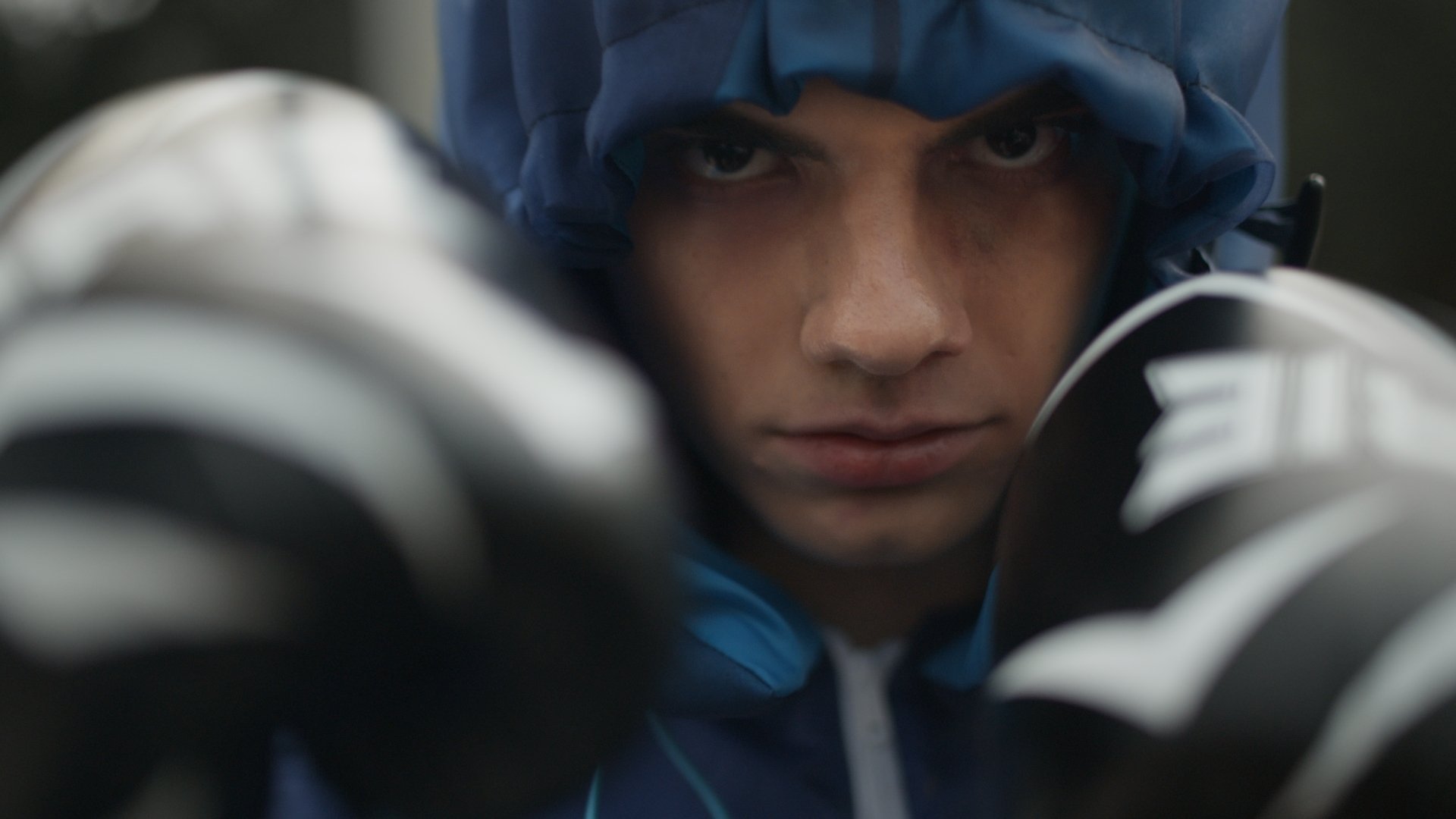Close-up of a figure in a blue hooded jacket and gloves - Wrocław Fashion Week Collections