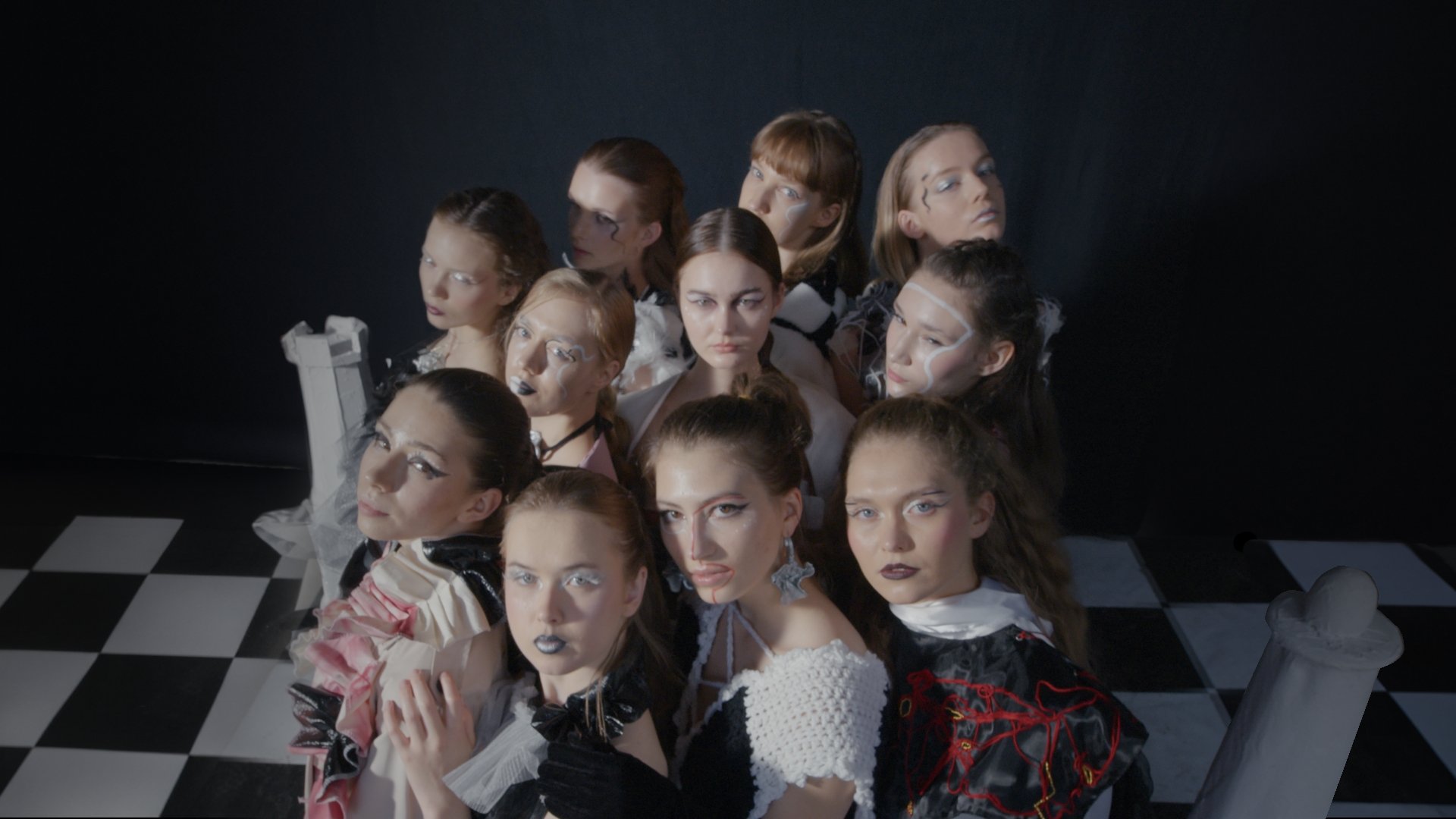 Group of models in dark patterned outfits standing on a checkered floor - Wrocław Fashion Week Collections